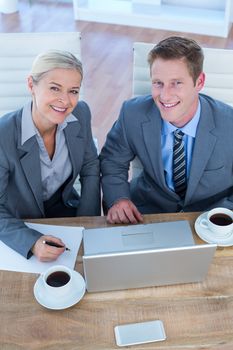 Smiling business people using laptop in the office