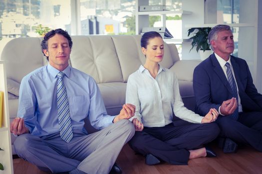Business people meditating in lotus pose in the office