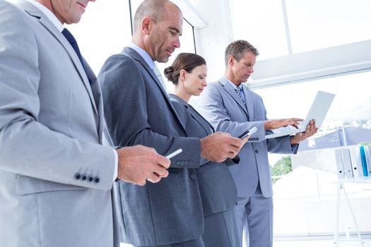 Business colleagues using their multimedia devices in the office