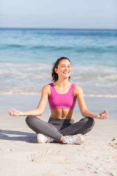 Fit woman doing yoga beside the sea at the beach 