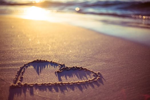 one heart drawn in the sand at the beach