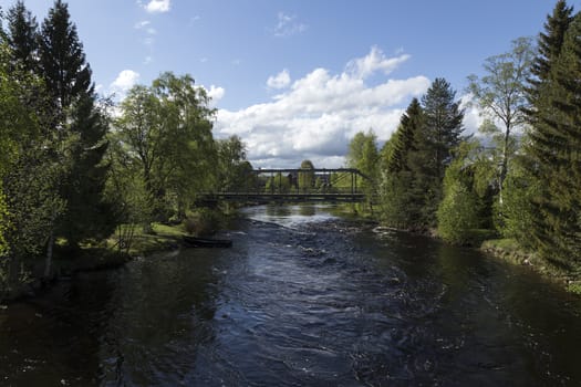 A bridge over a stream with a boat in a nature scene