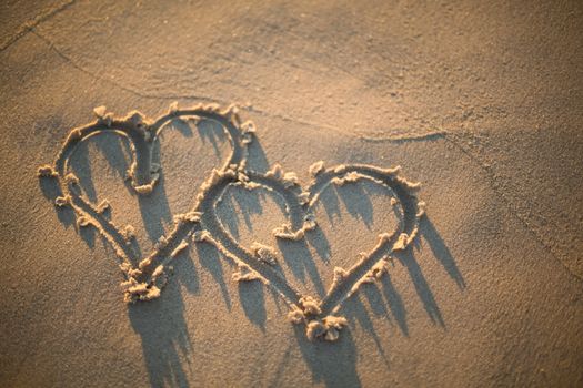 two hearts drawn in the sand on the beach