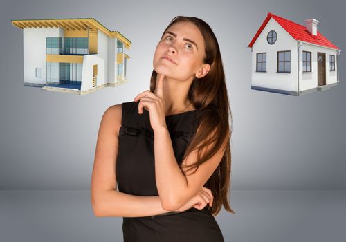 Business woman thinking over house and cottage. Gray gradient background