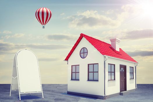 White house with red roof, brown door. Background sun shines brightly and flying hot air balloon. Near with house sidewalk sign. Blue sky