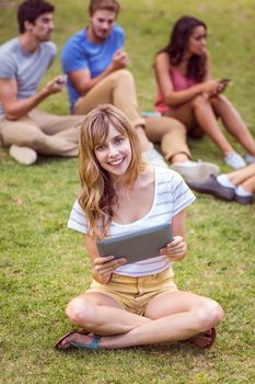 Pretty blonde using tablet in the park on a sunny day