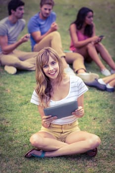 Pretty blonde using tablet in the park on a sunny day