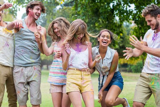 Happy friends throwing powder paint on a summer day 