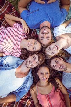 Happy friends in the park huddling in cirlce on a summer day