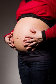 hands embrace a belly of the pregnant woman