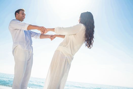 Romantic casual young couple holding hands and standing at the beach