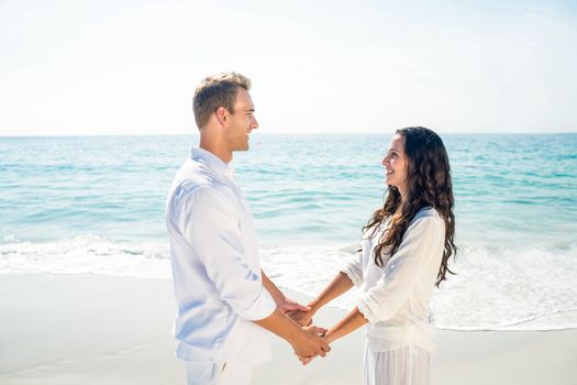 Romantic casual young couple holding hands and standing at the beach