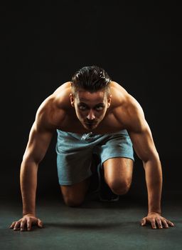 Sport attractive man doing fitness exercises on the black background