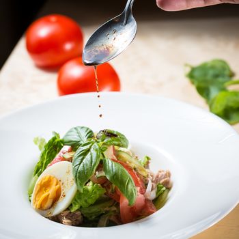 Closeup of plate of spring mix salad with strawberry, eggs and tuna