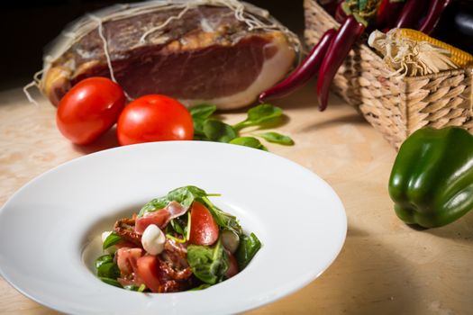 Salad with strawberry, prosciutto, herbs, cottage cheese and blackberry balsamic vinegar. Shallow dof.