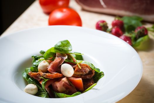Salad with strawberry, prosciutto, herbs, cottage cheese and blackberry balsamic vinegar. Shallow dof.