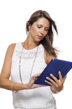 Attractive young business woman standing chatting on a mobile while simultaneously reading a tablet computer with a smile, isolated on white