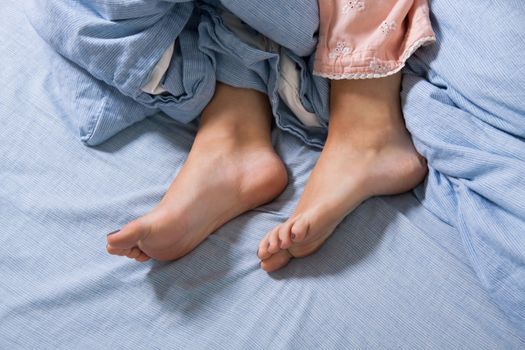 Close up Bare Feet of a Young Woman Lying Down on a Blue Bed, Captured in High Angle View.