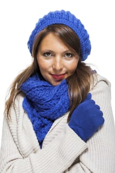 Close up Pretty Smiling Young Woman Wearing Winter Knit Outfit with Blue Bonnet, Scarf and Gloves. Captured in Studio with White Background While Looking at the Camera.