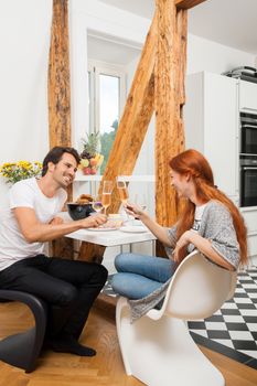 Young Couple Sitting at the Table and Slicing Freshly Baked Bread for their Ham Sandwich.