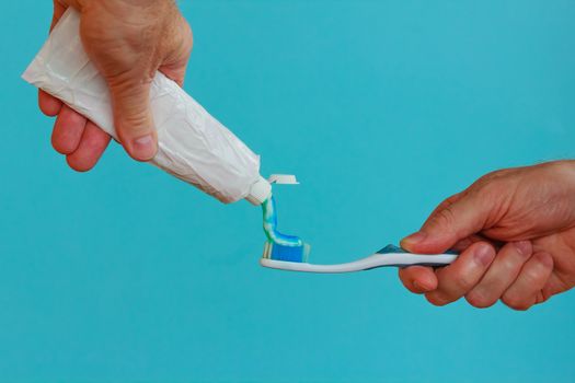 a man crushes the toothpaste with his hand to brush your teeth with a toothbrush
