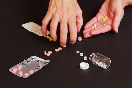 a woman collects too many tablets from jars and blisters