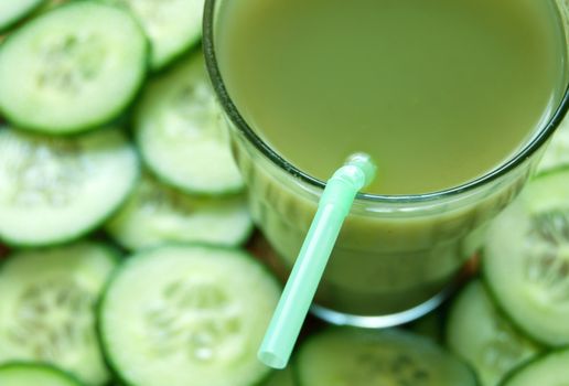 Fresh vegetable detox juice with cucumber slices in the background