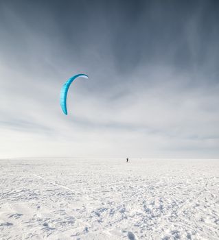 Kite surfer being pulled by his kite across the snow