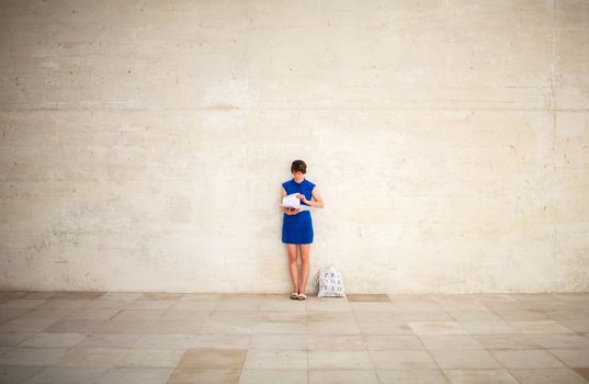 VENICE, ITALY - MAY 06: Girl leaning against the wall reading during the 56th Venice Biennale on May 06, 2015