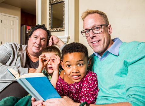 Attractive gay couple reads a book to their children