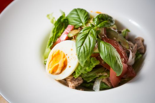 Closeup of plate of spring mix salad with strawberry, eggs and tuna