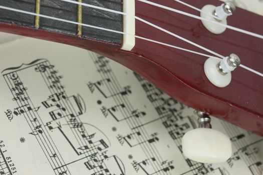 Close up of a ukulele rested on sheet music