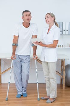 Man with crutch speaking with his doctor in medical office