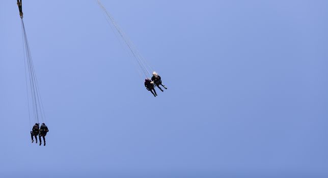 A closer view in a some persons in a ride high up in the air on an amusement field