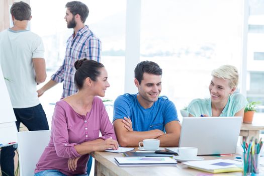 Creative business people using laptop in meeting at office