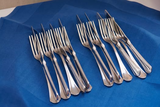 Cutlery sets with forks and knives on a clue tablecloth                               