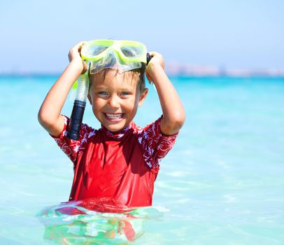 Portrait of happy cute boy wearing snorkeling mask ready to dive in the sea