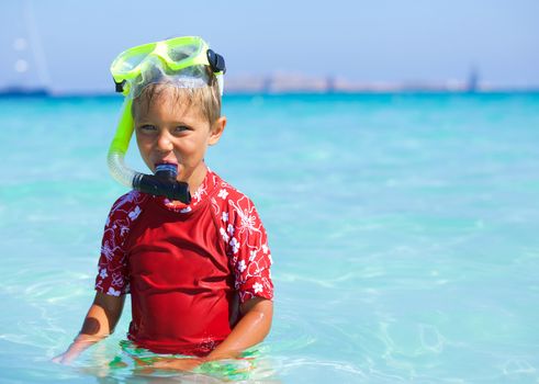 Portrait of happy cute boy wearing snorkeling mask ready to dive in the sea