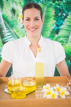 Portrait of a smiling beauty therapist holding tray of beauty treatments at the spa