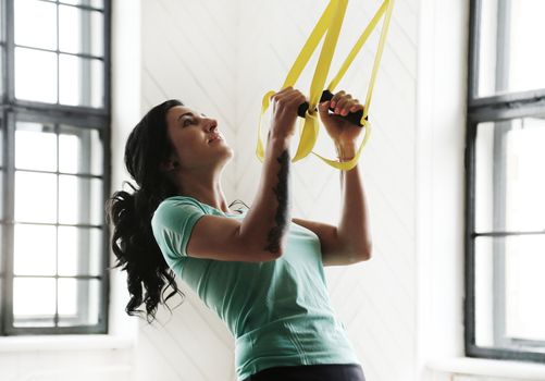 TRX. Beautiful woman at gym