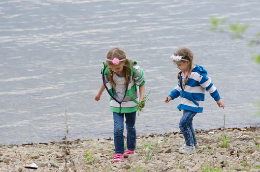 Two children enthusiastically walk along the river bank, and something to look for and collect