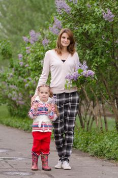 portrait of a beautiful young girl and the daughter of European type, with a bouquet of lilac in the hands of