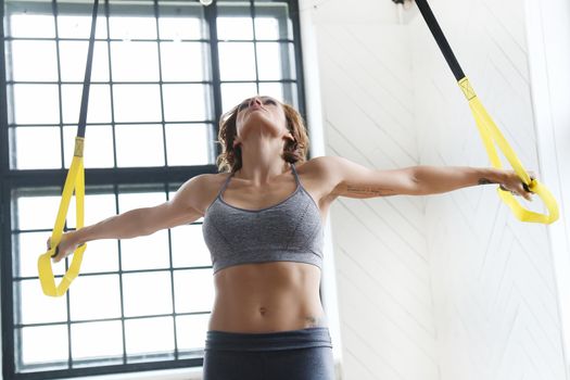 TRX. Beautiful woman at gym