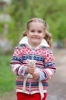 Half-length portrait four-year girl in a jacket with a bouquet of dandelions in the hands of