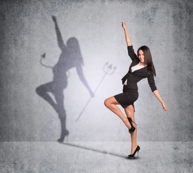 Businesswoman with shadow showing devil side on wall texture background, looking at camera