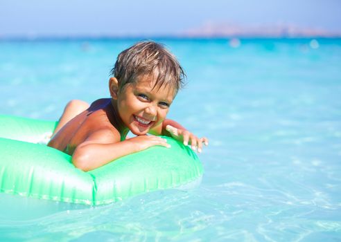 Happyboy playing on the inflatable rubber circle in the sea