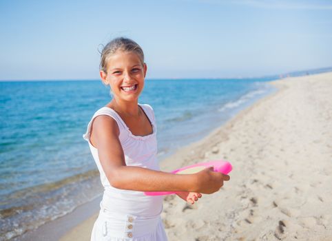 Happy cute girl playing frisbee on beach