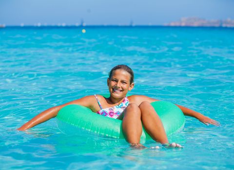 Beautiful girl relaxing on the inflatable rubber circle in the sea