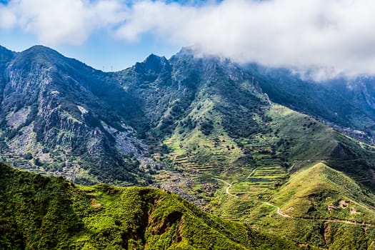 Mountains or rock with clouds over peak and road