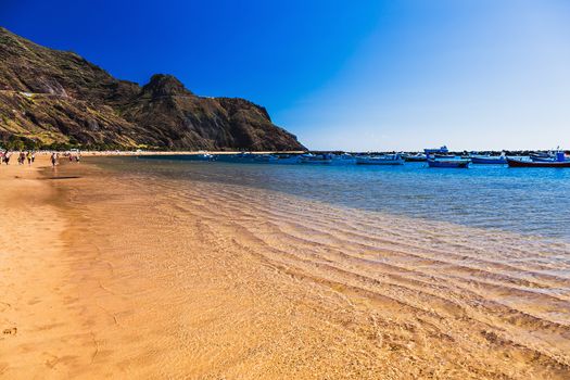 Beach Las Teresitas with water and waves on yellow sand on coast or shore of Atlantic ocean on Tenerife Canary island, Spain. Mountain at the background